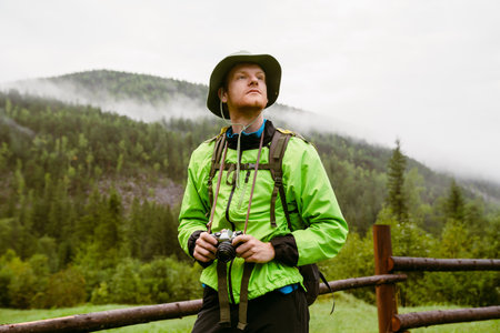 Young white man wearing trekking equipment using camera while hiking in mountain forest