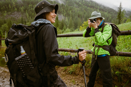 Young man tourist with backpack taking photos of her girlfriend on vintage camera during hiking in...