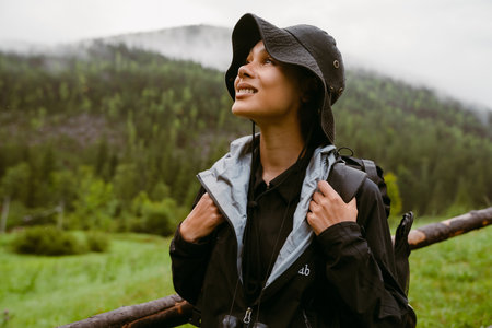 Young smiling african woman tourist with backpack looking away during hiking in mountainsの写真素材