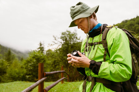Young white man wearing trekking equipment using camera while hiking in mountain forestの写真素材
