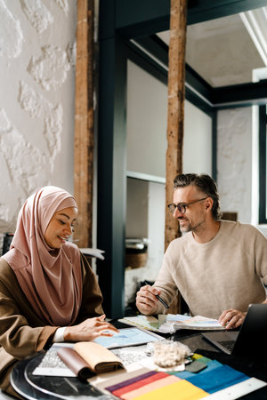 Multiracial cheerful woman and man designers working together in workshopの写真素材