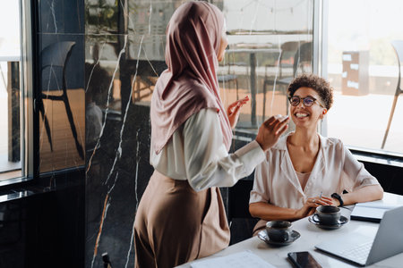 Middle-aged businesswoman and her female assistant talking together while working in officeの写真素材