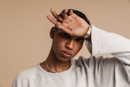 Portrait of young handsome stylish serious african man with hand on his forehead looking at camera ,...