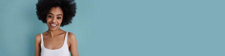 Happy african american girl smiling and looking at camera isolated over blue background