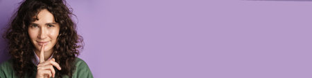 Pretty lovely young girl making silence gesture over gray background