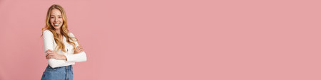 Beautiful lovely girl with long hair standing isolated over pink background, posing, arms folded