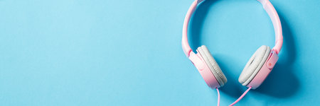 Overhead view of a pink wired headphones lying to the right of the camera in the blue studioの写真素材