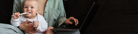 Happy mother with her baby son working on laptop computer at home