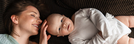 Happy mother and her baby boy cuddling on a couch at home, top view