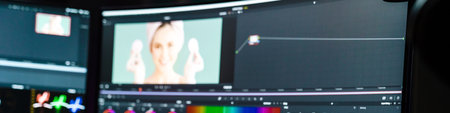 Back view of a young white man video editor sitting in front of a big screen working on a video...