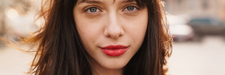 Close up of a young stylish brunette white woman with short hair standing on a street look at camera