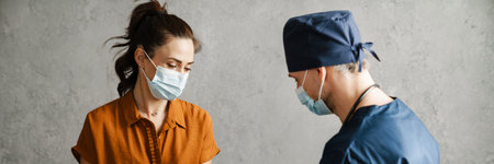 Doctor in protective medical mask measuring patients temperature in the cabinet