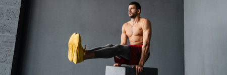 Young muscular shirtless sportsman exercising on a cube indoors