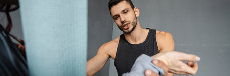Young muscular white sportsman trainer standing with a young woman talking training indoors
