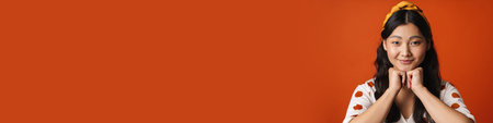 Smiling young asian woman in summer clothes standing over orange background, looking at camera