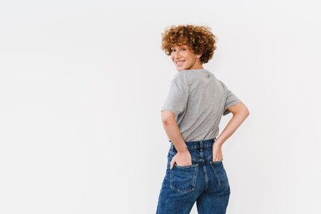 Ginger curly woman wearing t-shirt smiling and looking at camera isolated over white backgroundの写真素材