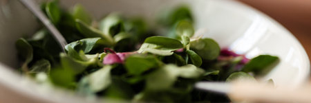 Closeup photo of plate with green salad and spoon indoorsの写真素材