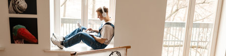 Young man in headphones using laptop while working on craft rug at home