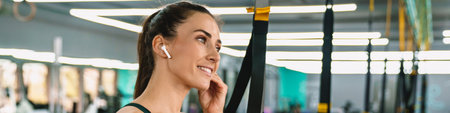 White sportswoman listening music with earphones while working out in gym