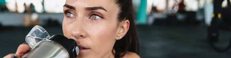 White sportswoman drinking water while working out in gymの写真素材