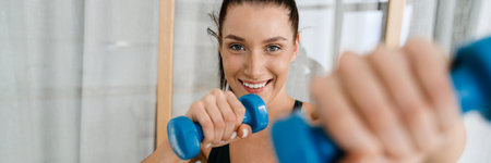 Happy brunette white woman lifting dumbbells at home in the living room