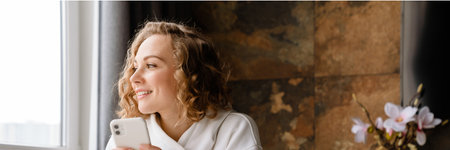White blonde woman using mobile phone and having breakfast at home
