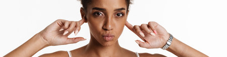 Young black woman in tank top making kiss lips and plugging her ears isolated over white backgroundの写真素材
