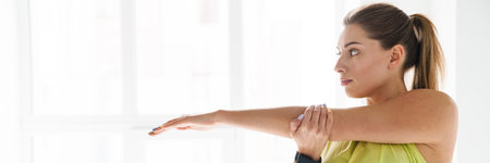 Young white sportswoman doing exercise while working out indoorsの写真素材