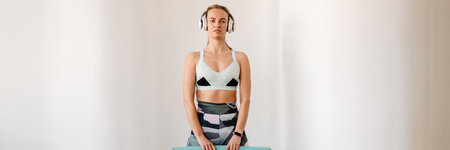 Young sportswoman with prosthesis posing with fitness mat indoors