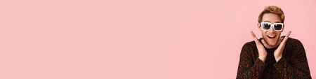 Happy mid aged blonde gay man in sunglasses standing over pink background looking at camera close up