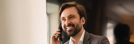 Smiling mid aged white businessman leaning on a hotel table talking on mobile phone