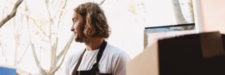 Young white cafe worker in apron taking delivery outdoors
