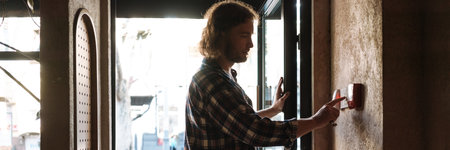 Young white cafe worker in plaid shirt pressing buttons indoors