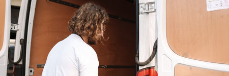 Young white cafe worker in apron taking delivery outdoors