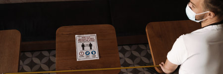 Young white cafe employee in face mask measuring while working indoorsの写真素材