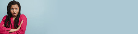 Young black shocked woman with pigtails expressing surprise at camera isolated over blue background