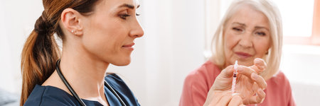 A female doctor wants to give insulin injection to her elderly patient in the bright room