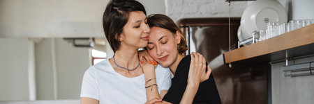 A positive lesbian couple girls hugging and leaning on the shoulder while standing in the light...