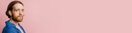 Young ginger man with beard posing and looking at camera isolated over pink backgroundの写真素材