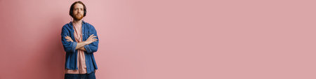 Young ginger bearded man listening music with headphones isolated over pink backgroundの写真素材