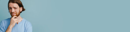 Young ginger man with beard frowning and looking at camera isolated over blue backgroundの写真素材