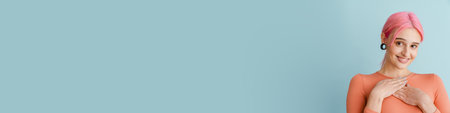 Young white woman with pink hair smiling while holding hands on her chest isolated over blue backgroundの写真素材