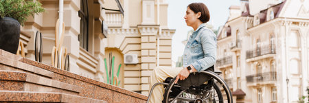 Brunette woman sitting in wheelchair by stairs on city streetの写真素材