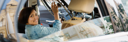 Brunette woman holding wheelchair while sitting in car on city streetの写真素材