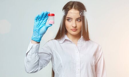 a woman doctor in gloves looks at the pills on a white backgroundの写真素材