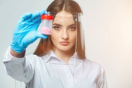 a woman doctor in gloves looks at the pills on a white backgroundの写真素材