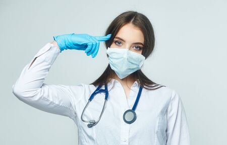 Covid19, coronavirus, a concept of healthcare and doctors. Portrait of a female doctor who shows a stop gesture! puts on a medical mask to prevent infection with the virusの写真素材