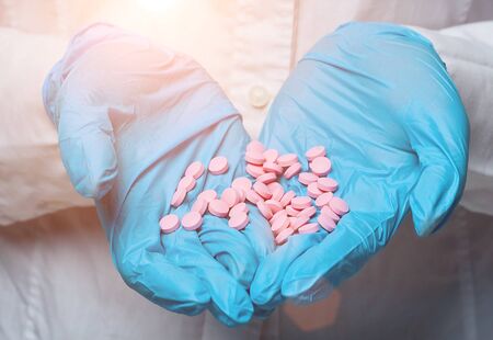 the gloved doctor shows the tablets in the palm of his handの写真素材