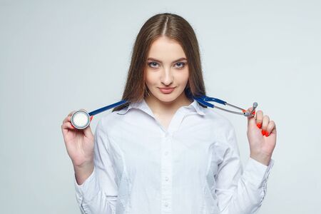 Portrait of a young woman doctor with a stethoscope on a white backgroundの写真素材