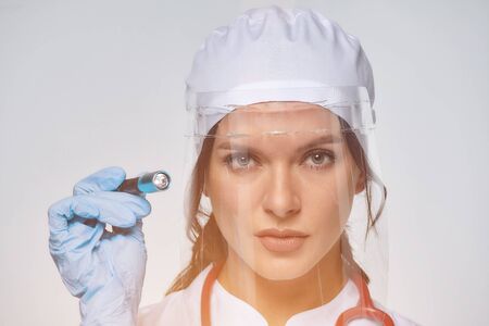 Medical concept of a female doctor in a white coat with a stethoscope, doctor. A female hospital worker looks at the camera and smiles, Studio, White backgroundの写真素材